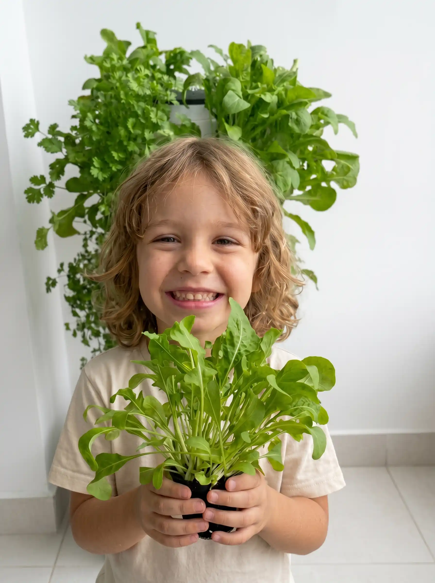 Criança sorrindo segurando muda de alface cultivada em sistema hidropônico indoor